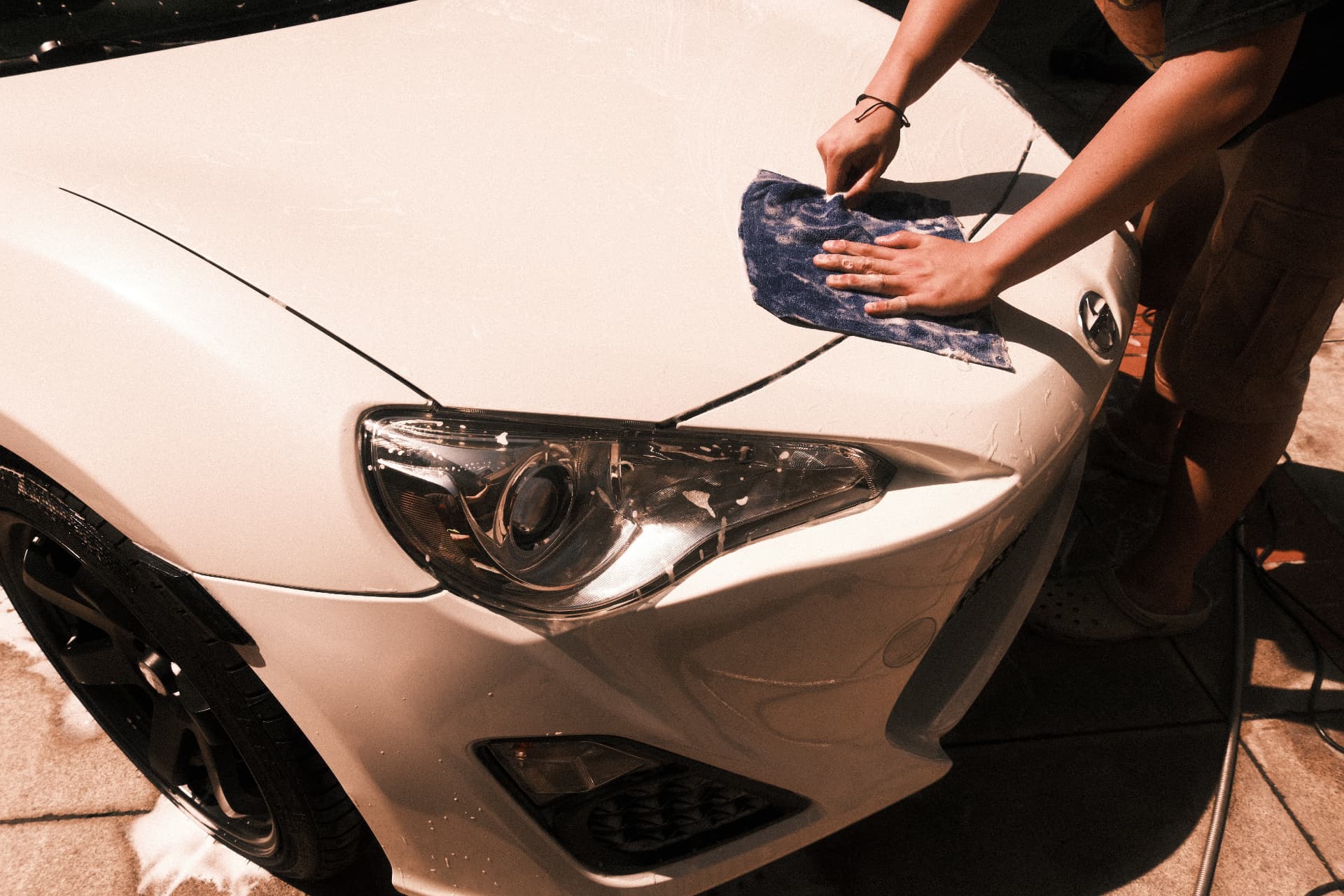 Hand washing the hood of a white coupe